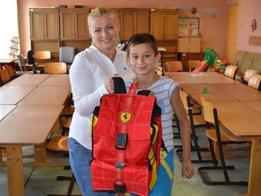 Betreuerin mit Kind und neuem Schulsack